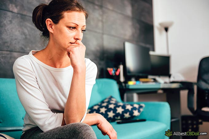 Best CBD oil for anxiety: an anxious woman sitting on a sofa.